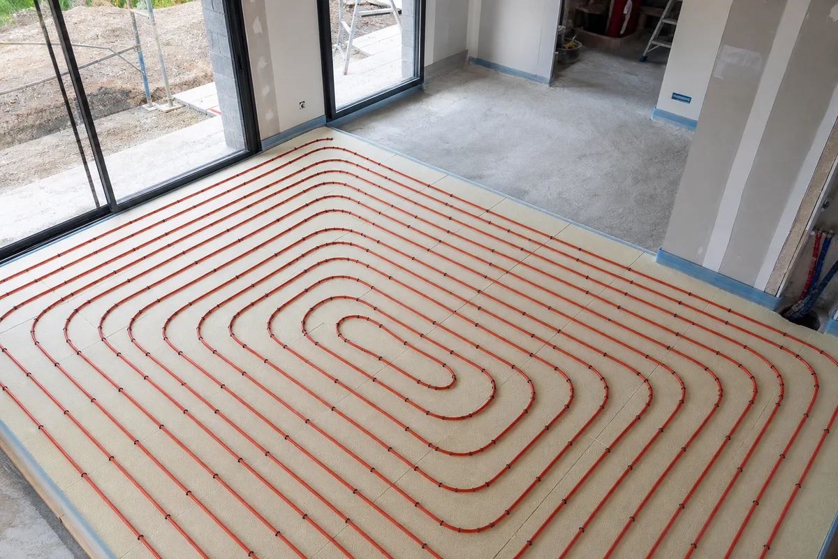 Tubes de plancher chauffant fixés en spirale sur une dalle isolante avant coulage de la chape